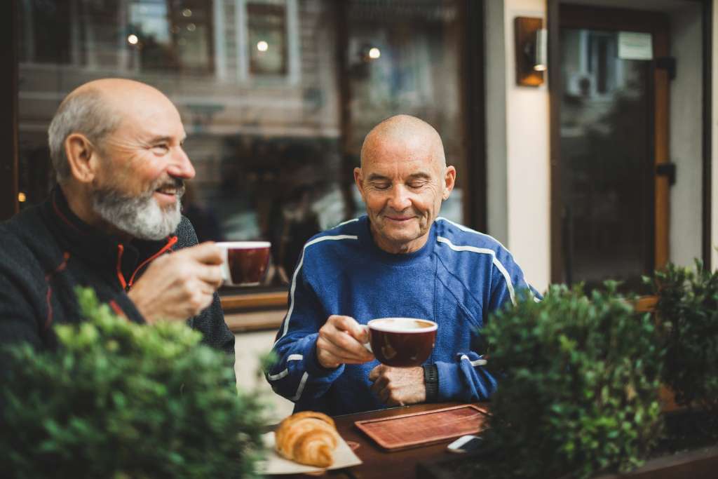 Two older adult men spending time connecting at the YMCA, perhaps after a group exercise class together. This illustrates how the Crossroads YMCA is a place older adults who want to be part of the Healthy Generation.